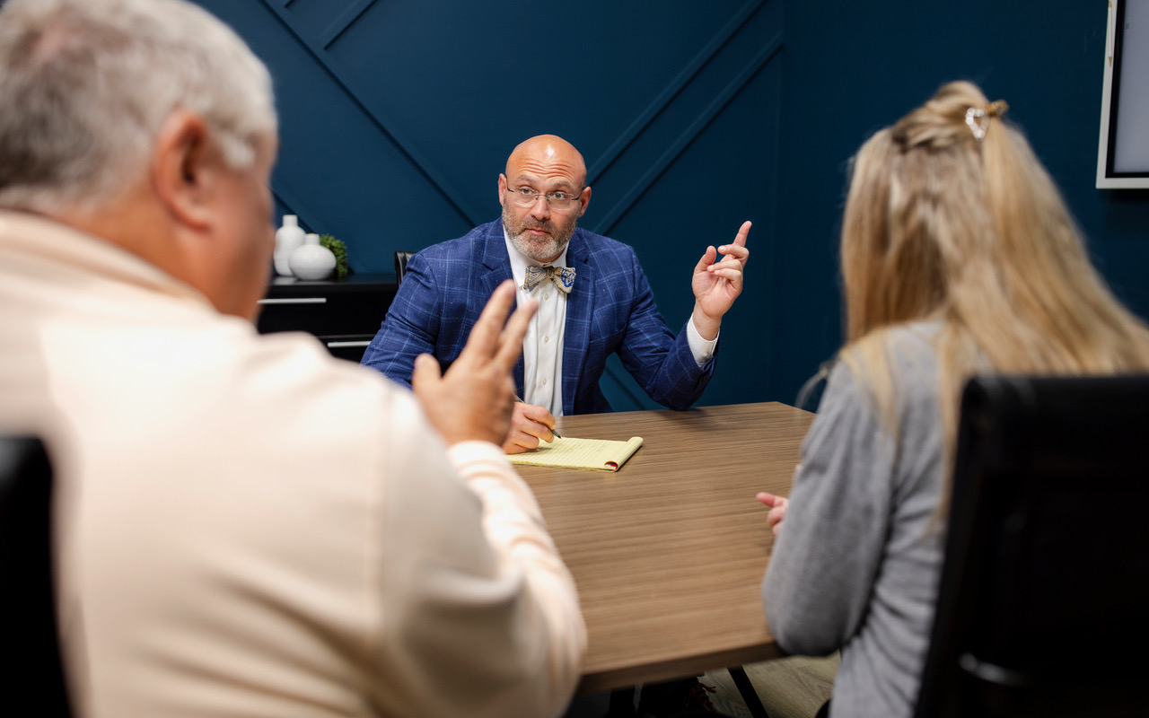 Mitchel Krause in conversation with two clients across a conference table